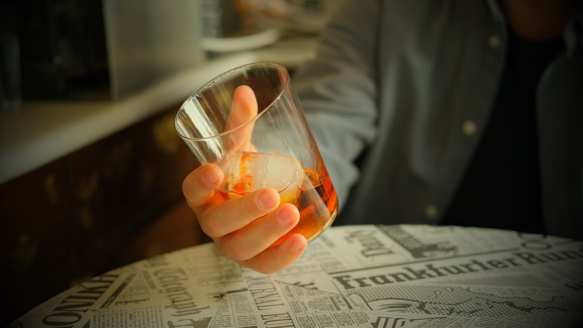 man holding a glass with whiskey on the rocks